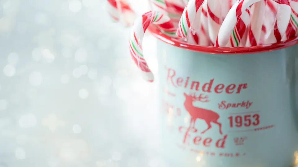 Rot-weiße Zuckerstangen in einer weihnachtlichen Tasse mit Rentiermotiv