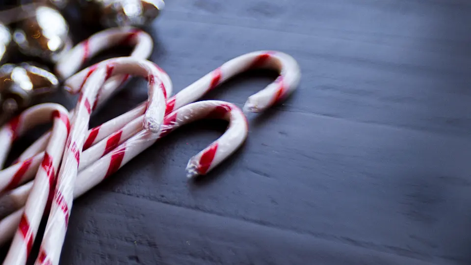 Mehrere Zuckerstangen mit rotweißen Streifen auf dunklem Holz
