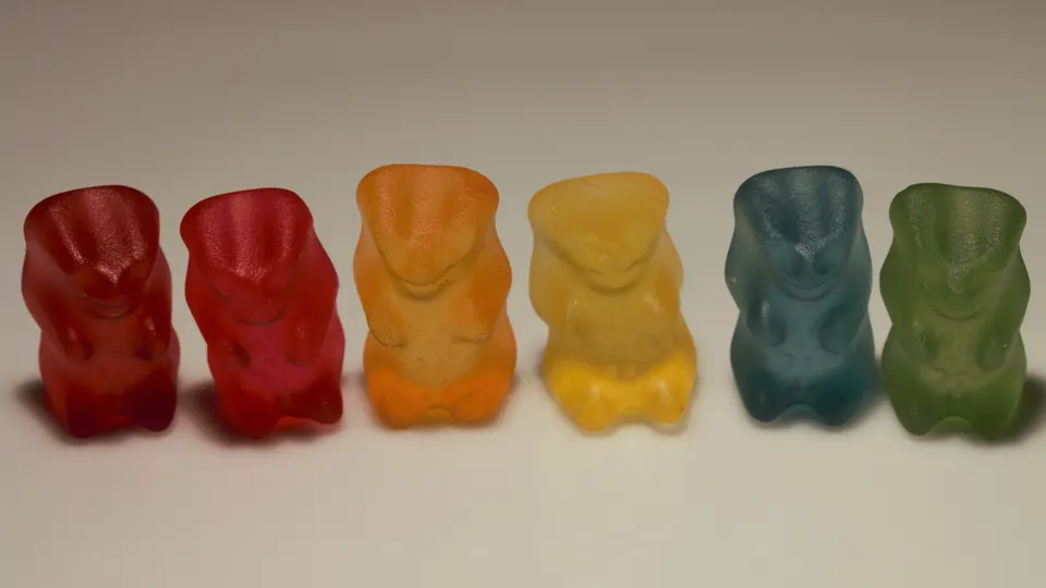 Sechs Gummibärchen in einer Reihe, von Rot über Orange bis Grün